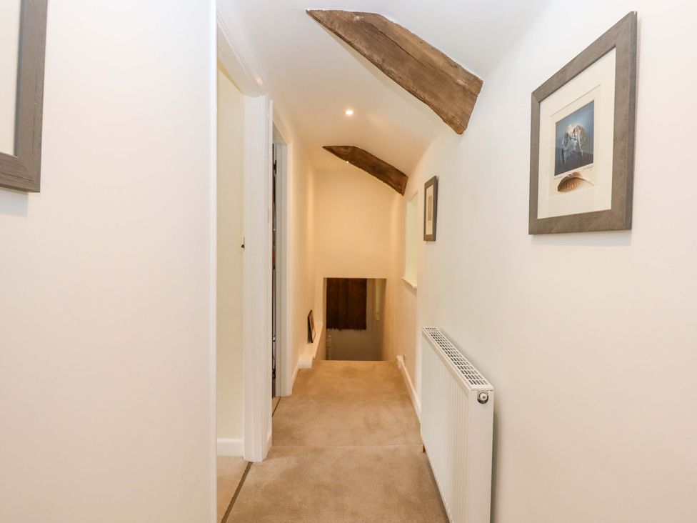 A hallway with framed pictures and a staircase at Town Farm Cottage in Barnstaple