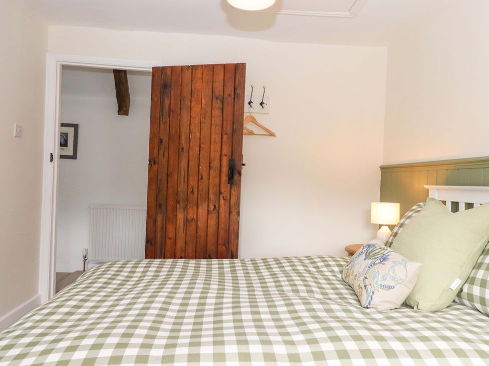 A bedroom with a bed and wooden door at Town Farm Cottage Barnstaple
