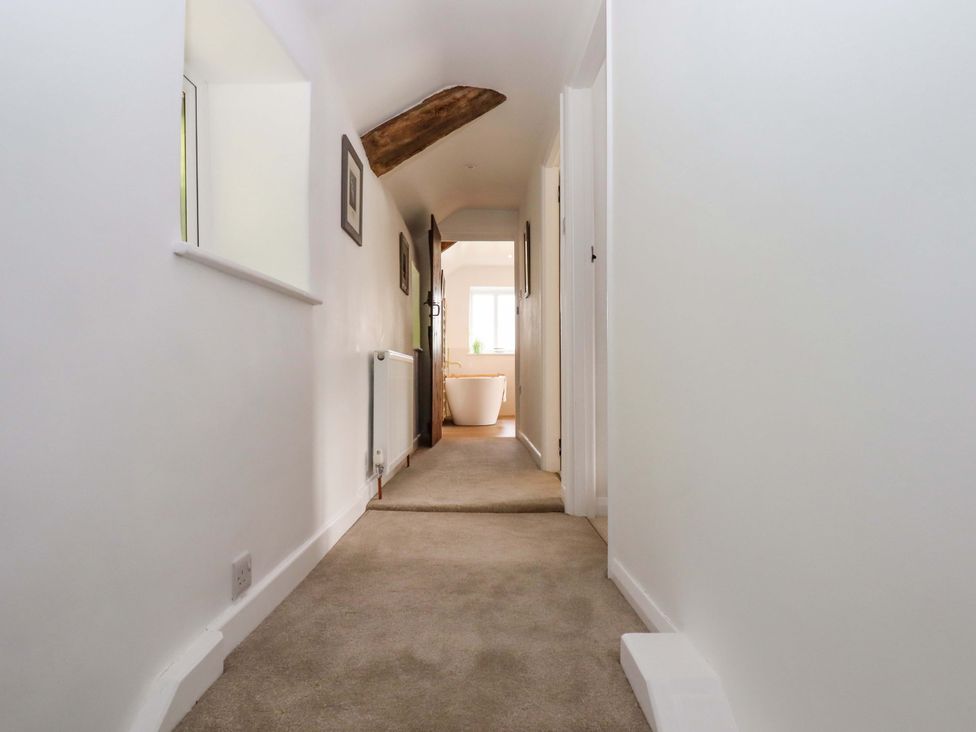 A hallway with a carpet, radiator and bathtub at Town Farm Cottage Barnstaple