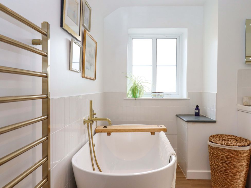 A bathroom with a bathtub and towel rack at Town Farm Cottage in Barnstaple