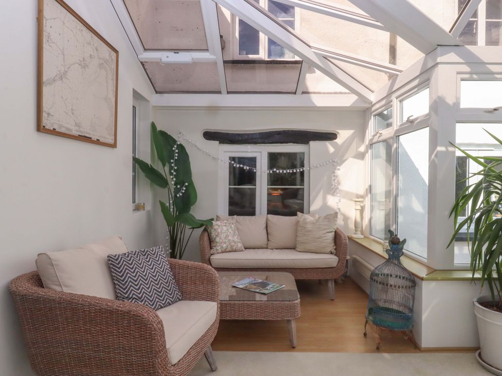 A conservatory with seating and plants at Town Farm Cottage Barnstaple