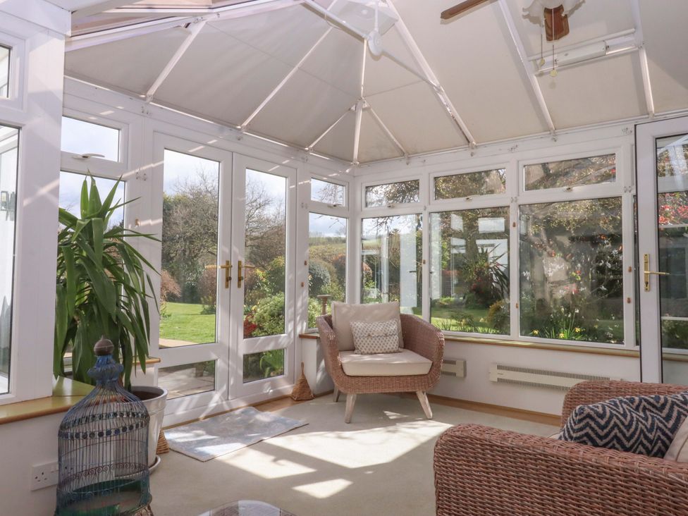 A conservatory with a plant and chairs at Town Farm Cottage in Barnstaple