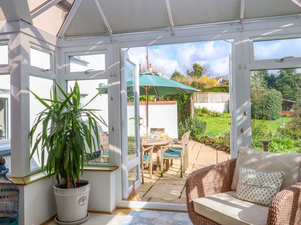 A conservatory with a plant and outdoor dining furniture at Town Farm Cottage Barnstaple