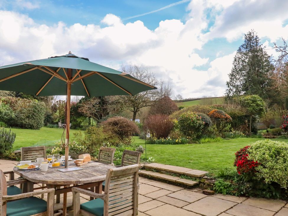 A garden with a table and chairs under an umbrella at Town Farm Cottage in Barnstaple