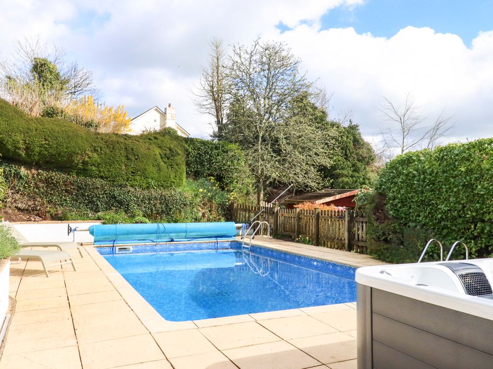 An outdoor area with a swimming pool and deck chairs at Town Farm Cottage in Barnstaple