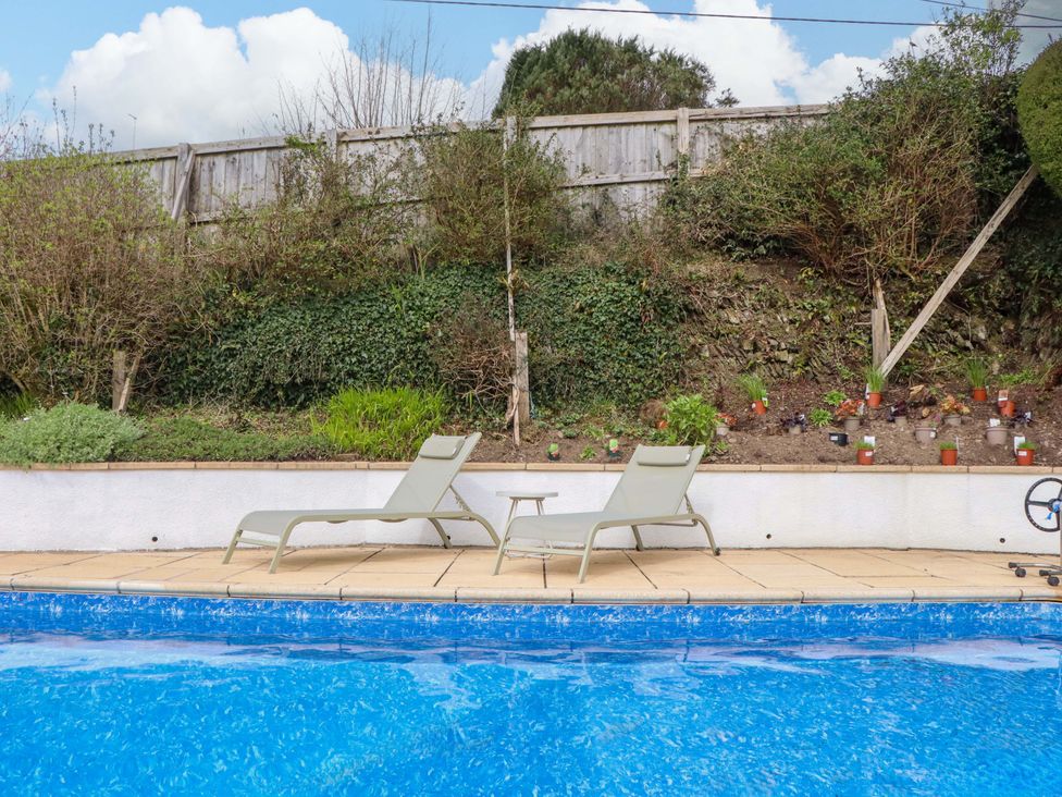 An outdoor area with a swimming pool and lounge chairs at Town Farm Cottage in Barnstaple