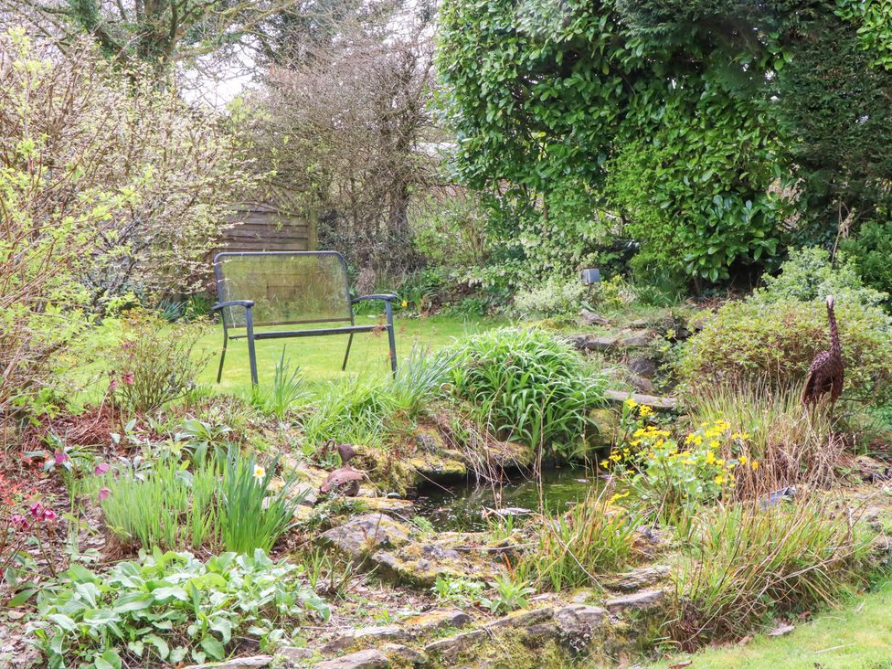 A garden with a bench and a pond at Town Farm Cottage Barnstaple
