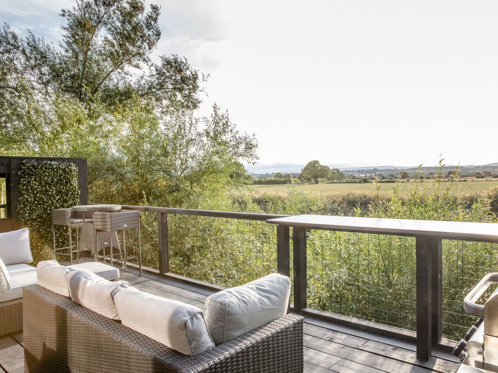 An outdoor patio with seating and bar stools at The Larch House Farndon