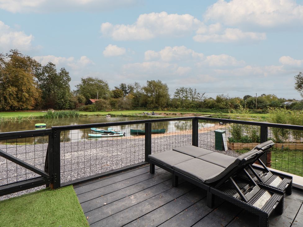 A deck with chairs overlooking a body of water at The Larch House in Farndon
