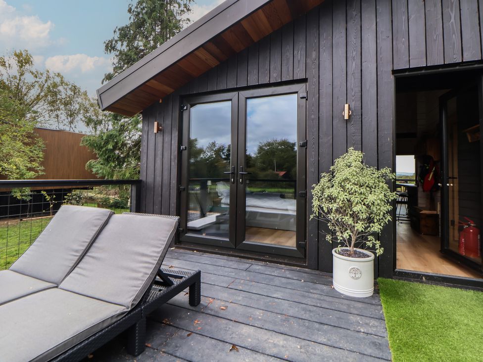 An outdoor deck with a lounge chair and sliding doors at The Larch House Farndon