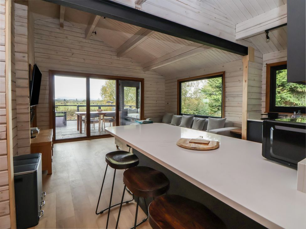 A kitchen with an island and bar stools at The Larch House in Farndon