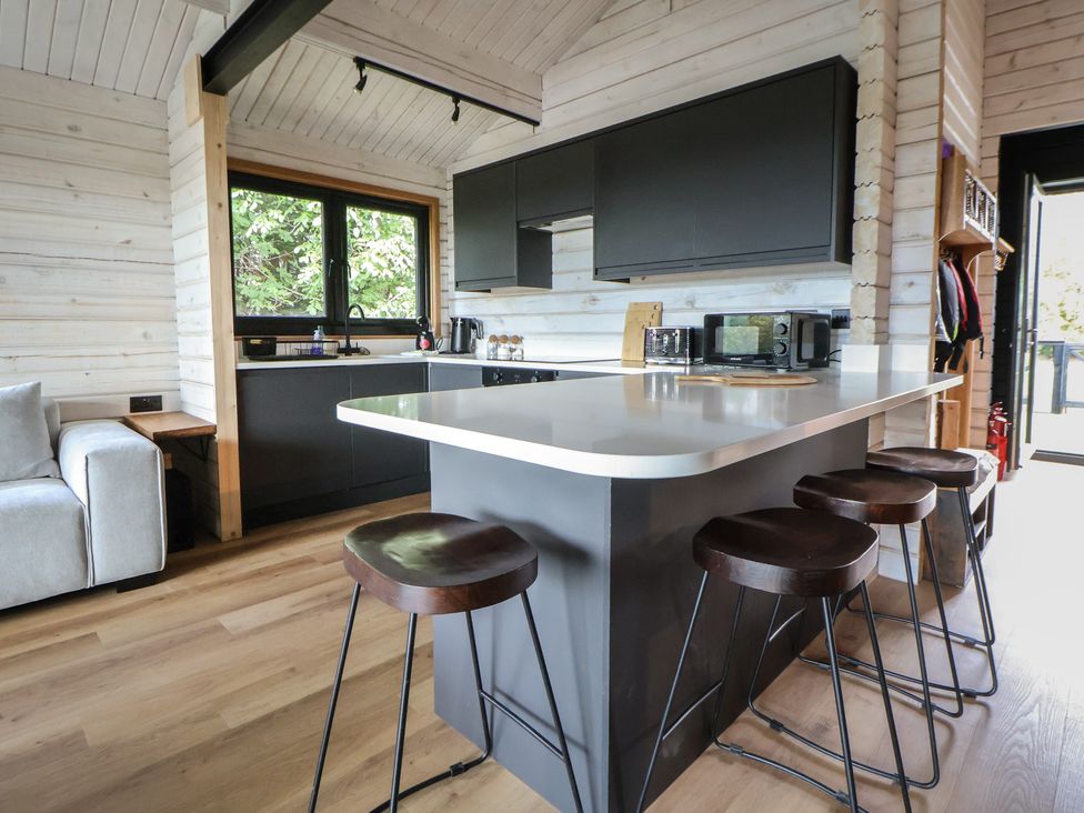 A kitchen with an island and bar stools at The Larch House in Farndon