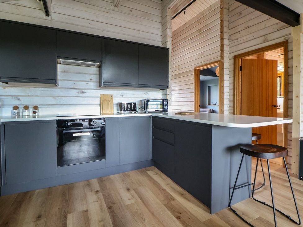 A kitchen with black cabinets and appliances at The Larch House in Farndon
