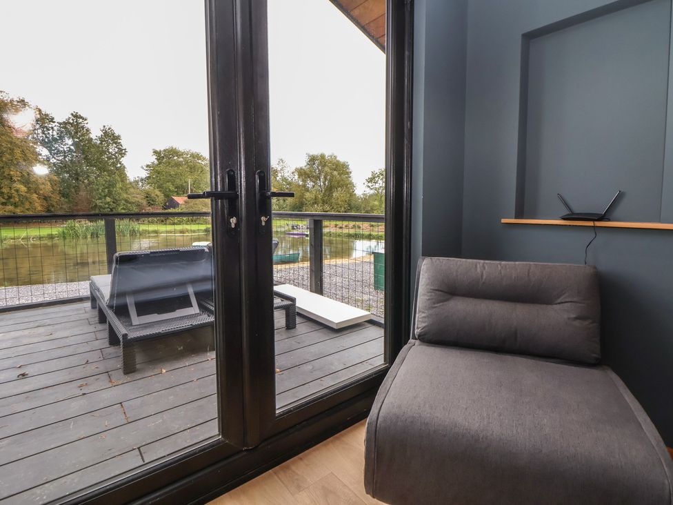 A chair near a window overlooking a river at The Larch House in Farndon