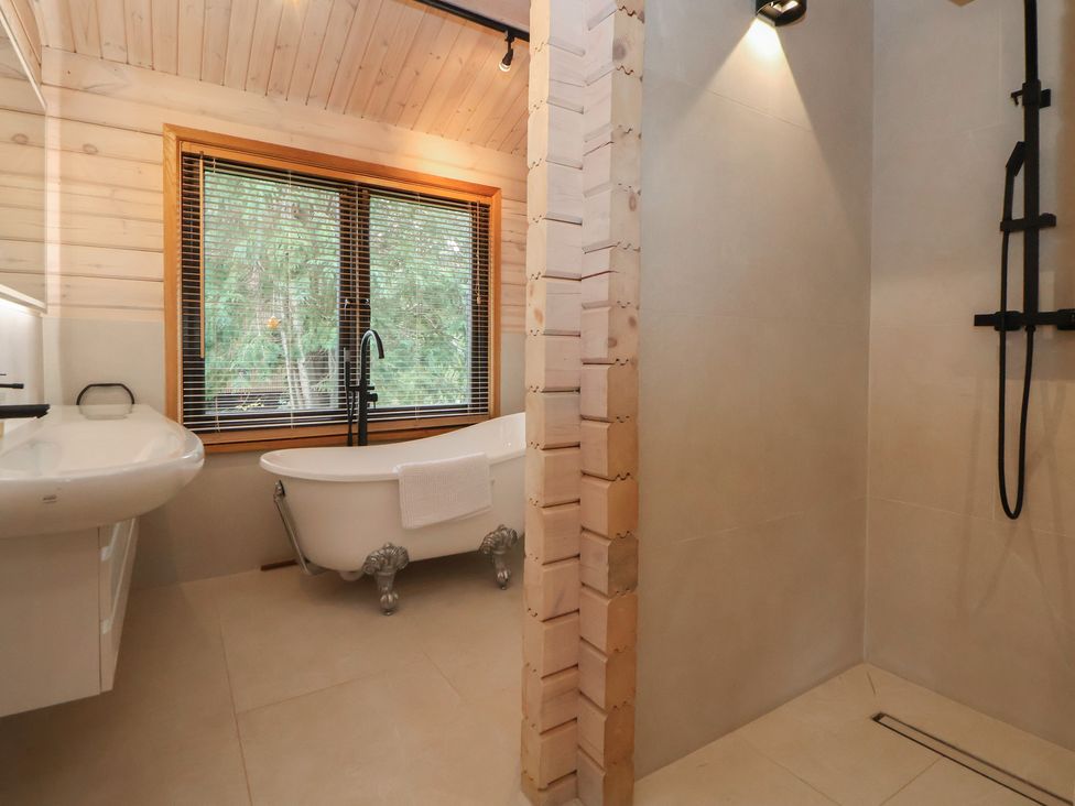 A bathroom with a bathtub, shower, and sink at The Larch House in Farndon