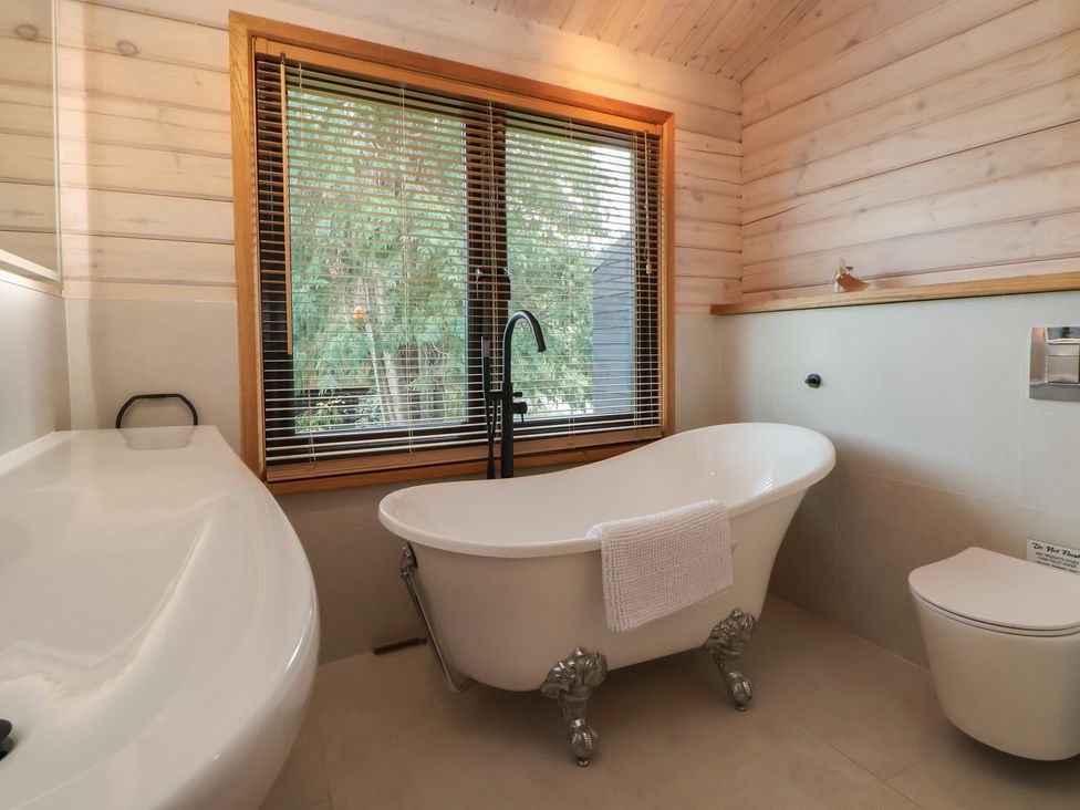 A bathroom with a bathtub and toilet at The Larch House in Farndon
