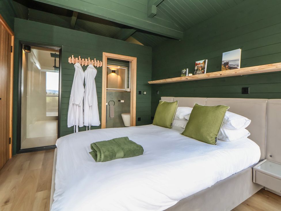 A bedroom with a bed and two robes at The Larch House in Farndon