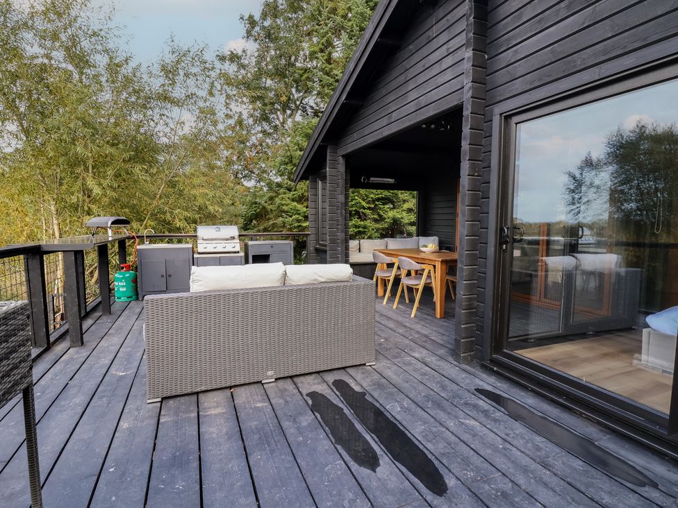 An outdoor deck with furniture and a grill at The Larch House in Farndon