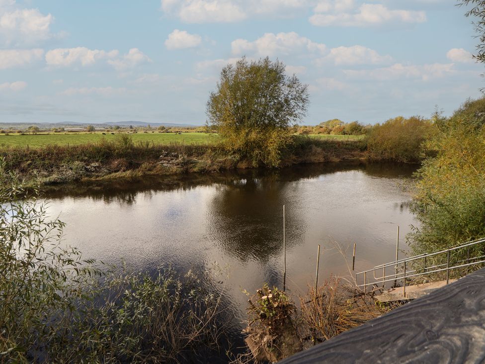 A river with trees and grass along the banks at The Larch House in Farndon