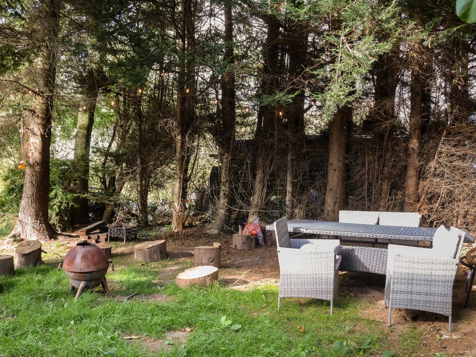 A garden with a table and chairs near a fire pit at The Larch House Farndon
