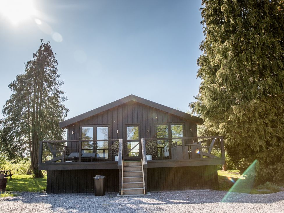 A house with a deck and stairs surrounded by trees at The Larch House in Farndon
