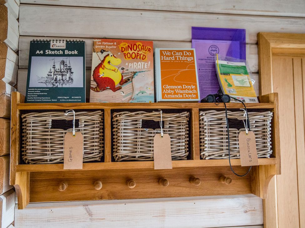 Shelves with books and storage baskets at The Larch House in Farndon