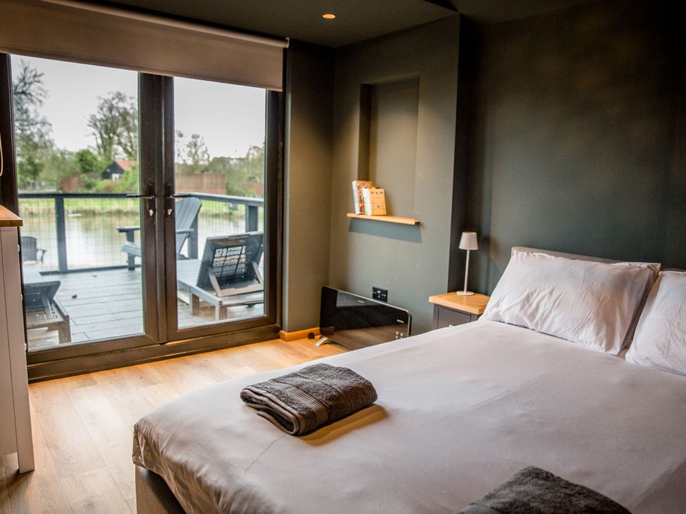 A bedroom with a bed and sliding doors leading to a deck at The Larch House in Farndon