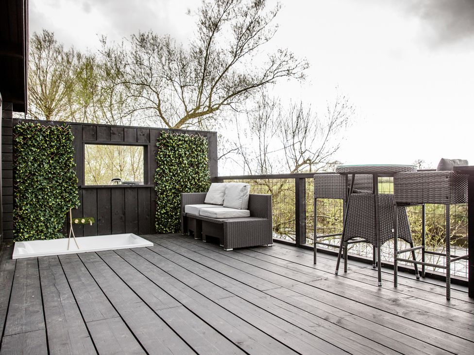 An outdoor area with a couch, bar table and stools at The Larch House in Farndon