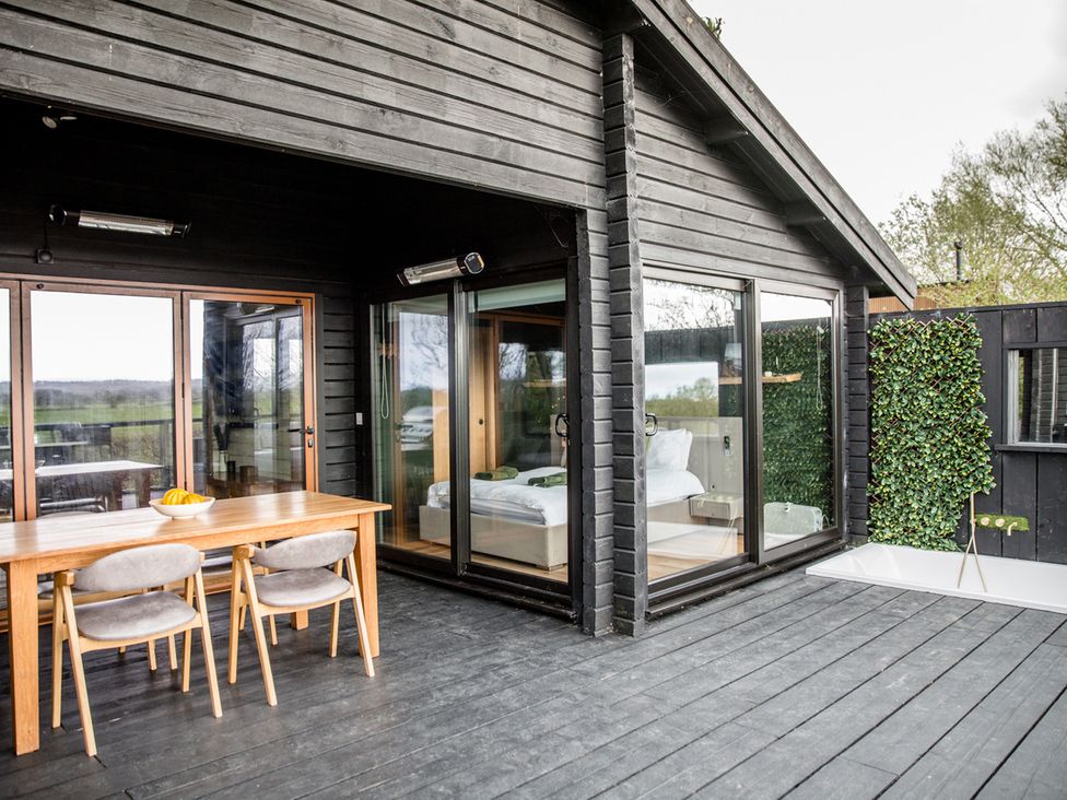 An outdoor patio with a dining table and chairs at The Larch House in Farndon