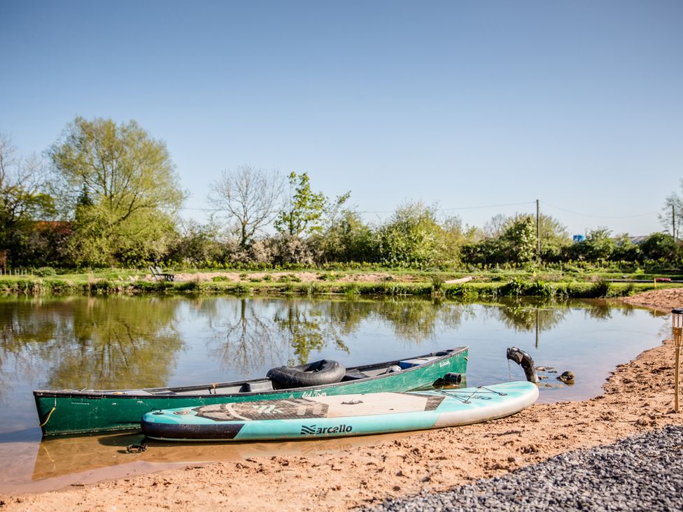 A canoe and stand-up paddleboard by the water at The Larch House in Farndon