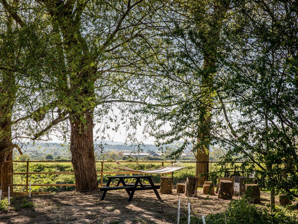 An outdoor area with a table and hammock surrounded by trees at The Larch House Farndon