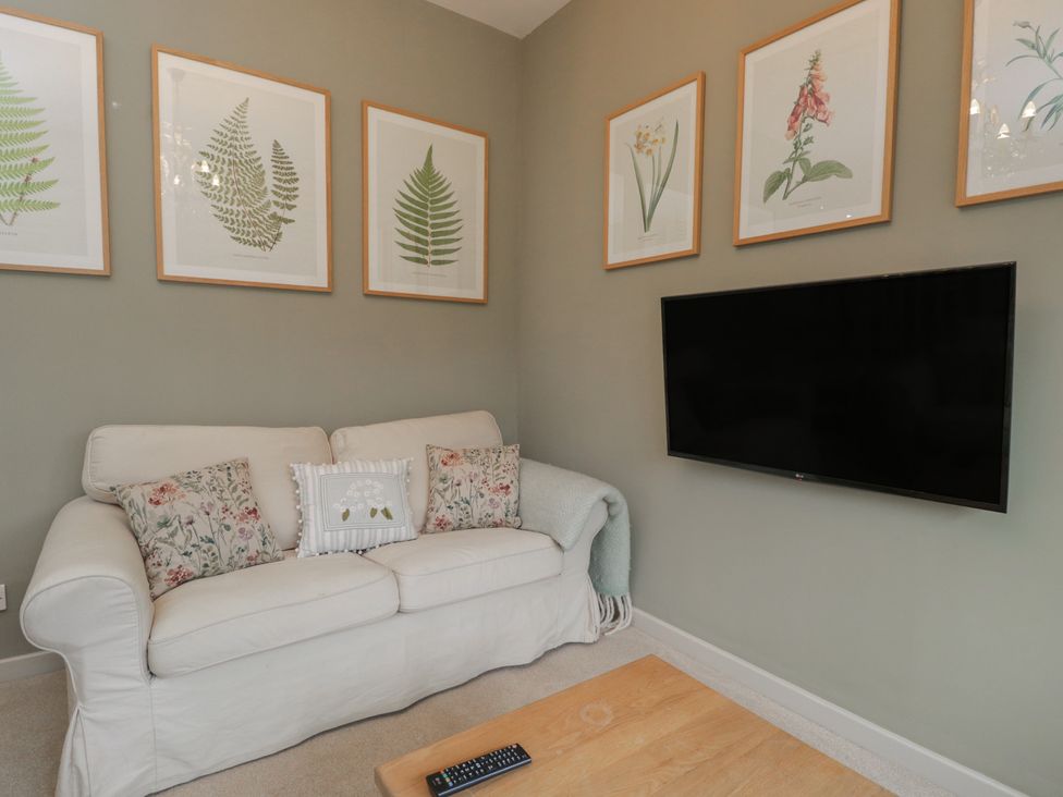 A living room with a white sofa and TV at Granary Cottage in 