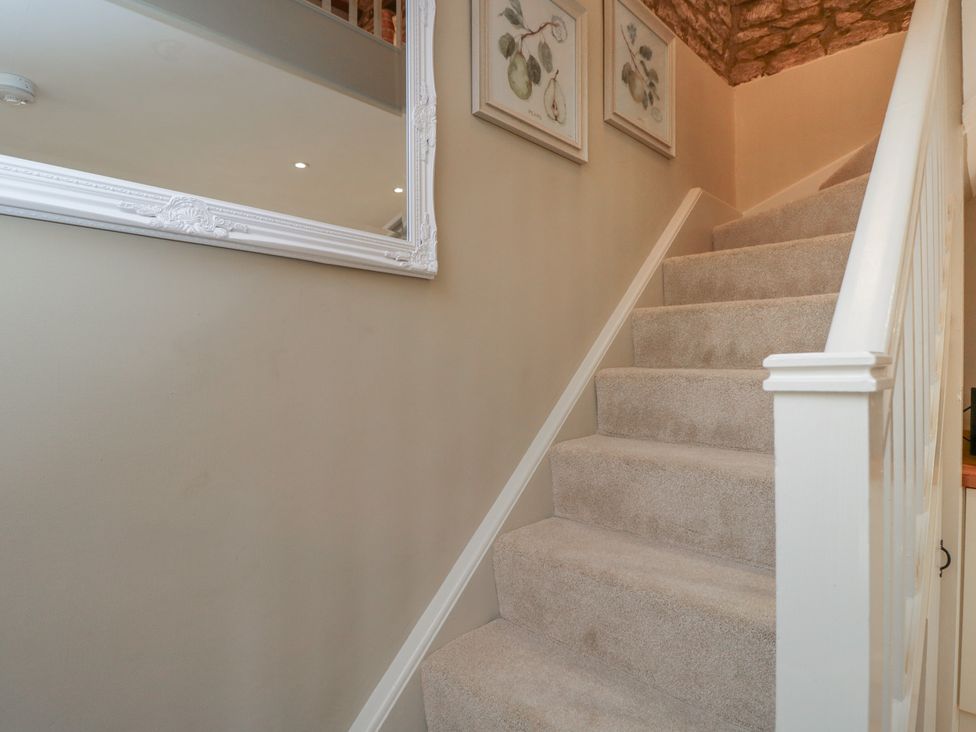 A staircase with a mirror and paintings at Granary Cottage in 