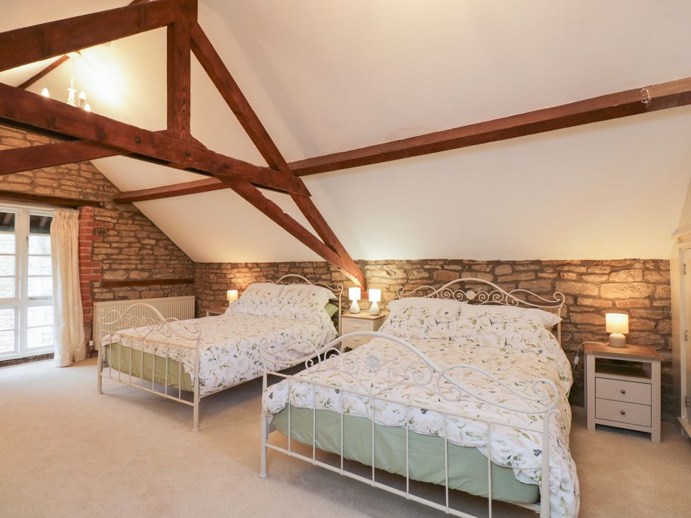 A bedroom with two beds and a stone wall at Granary Cottage