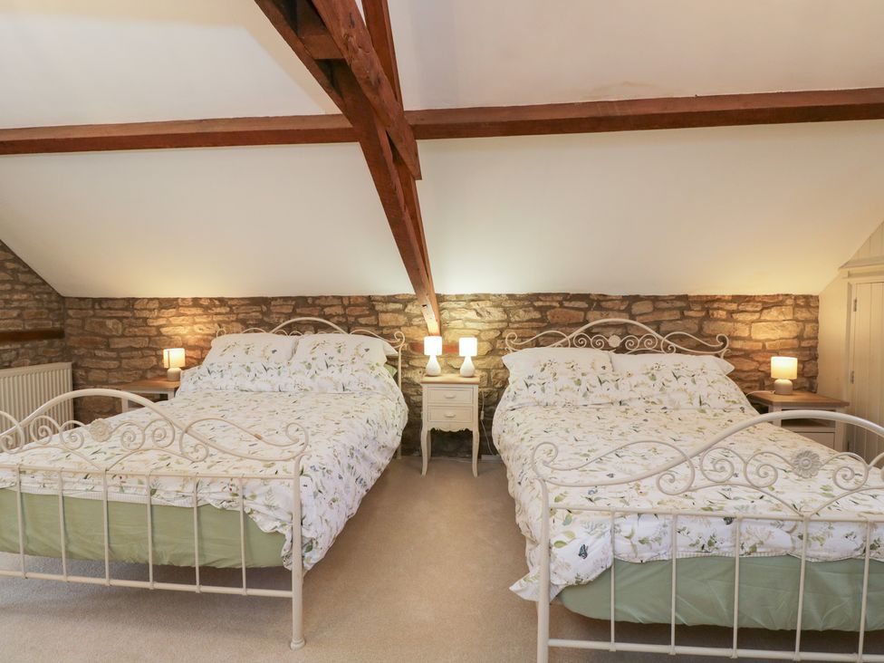 A bedroom with two beds and nightstands at Granary Cottage