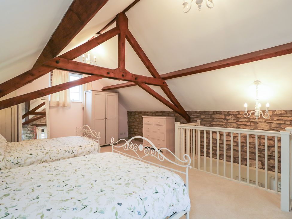A bedroom with two beds and a wardrobe at Granary Cottage