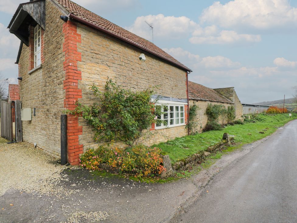 A stone building with a window and door beside a road at Granary Cottage