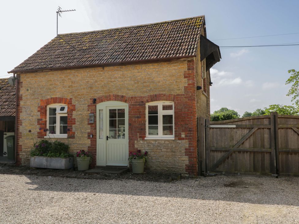 An outdoor view of a stone building with a door and windows at Granary Cottage in Lacock