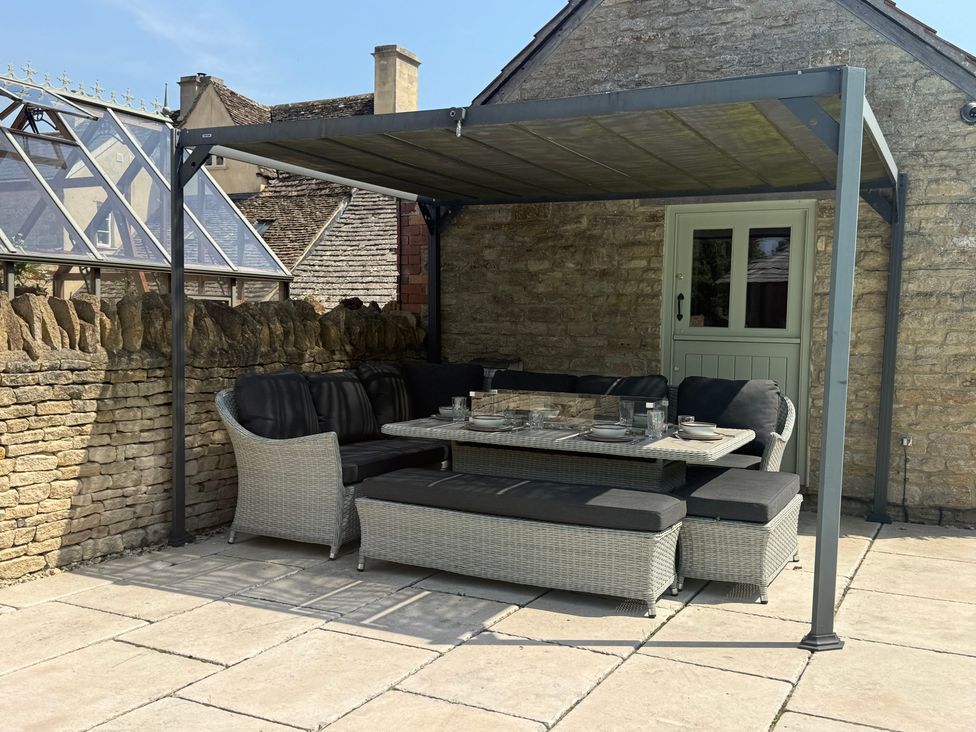 An outdoor seating area with a table and cushions at Granary Cottage in Lacock