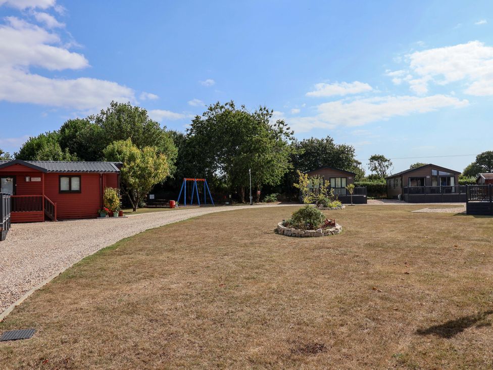 An outdoor area with cabins and a swing set at Cedar 1 Pinewood Retreat in Rousdon near Lyme Regis