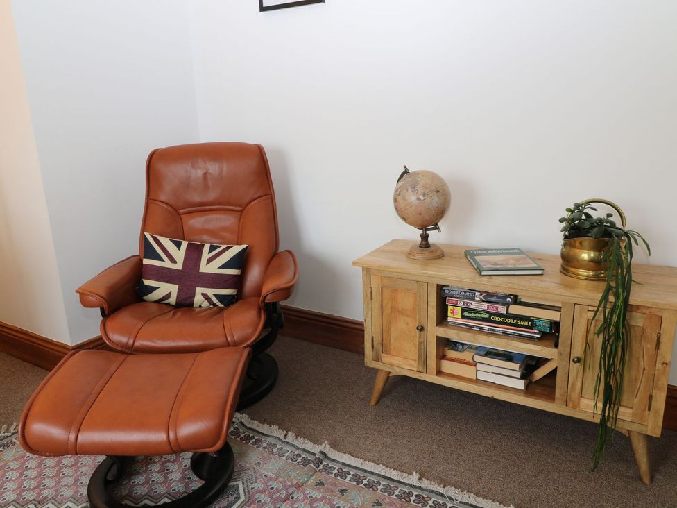 A living room with an armchair and bookshelf at Baywatch (St. David's View) Lynton