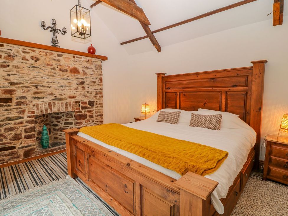 A bedroom with a wooden bed and stone fireplace at Baywatch (St. David's View) in Lynton