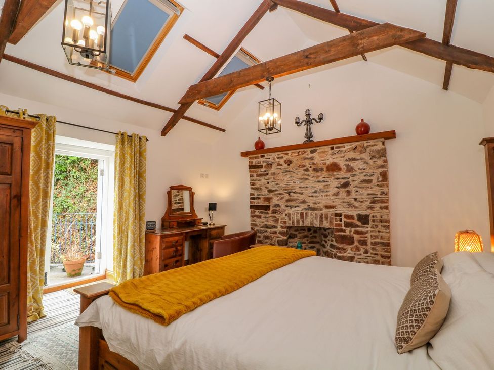 A bedroom with a wooden bed and fireplace at Baywatch (St. David's View) Lynton