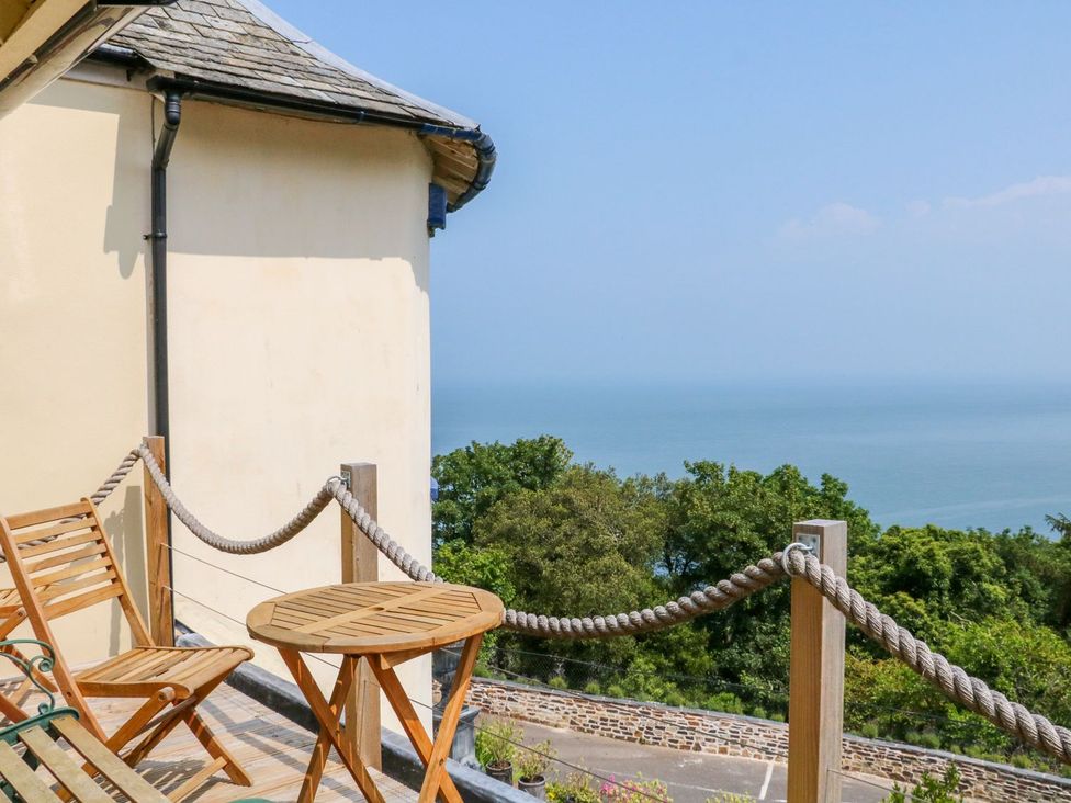 A balcony with a table and chairs overlooking the sea at Baywatch (St. David's View) Lynton