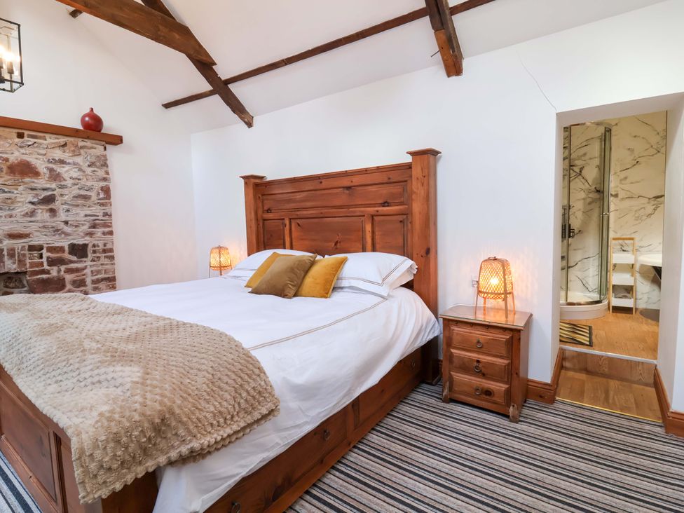A bedroom with a wooden bed and nightstand at Baywatch (St. David's View) in Lynton