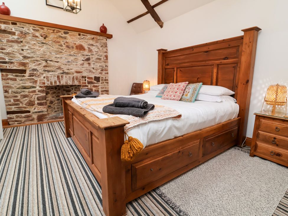 A bedroom with a wooden bed and a fireplace at Baywatch (St. David's View) Lynton