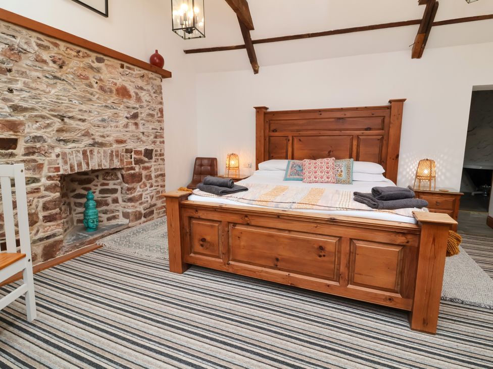A bedroom with a wooden bed and stone fireplace at Baywatch (St. David's View) Lynton