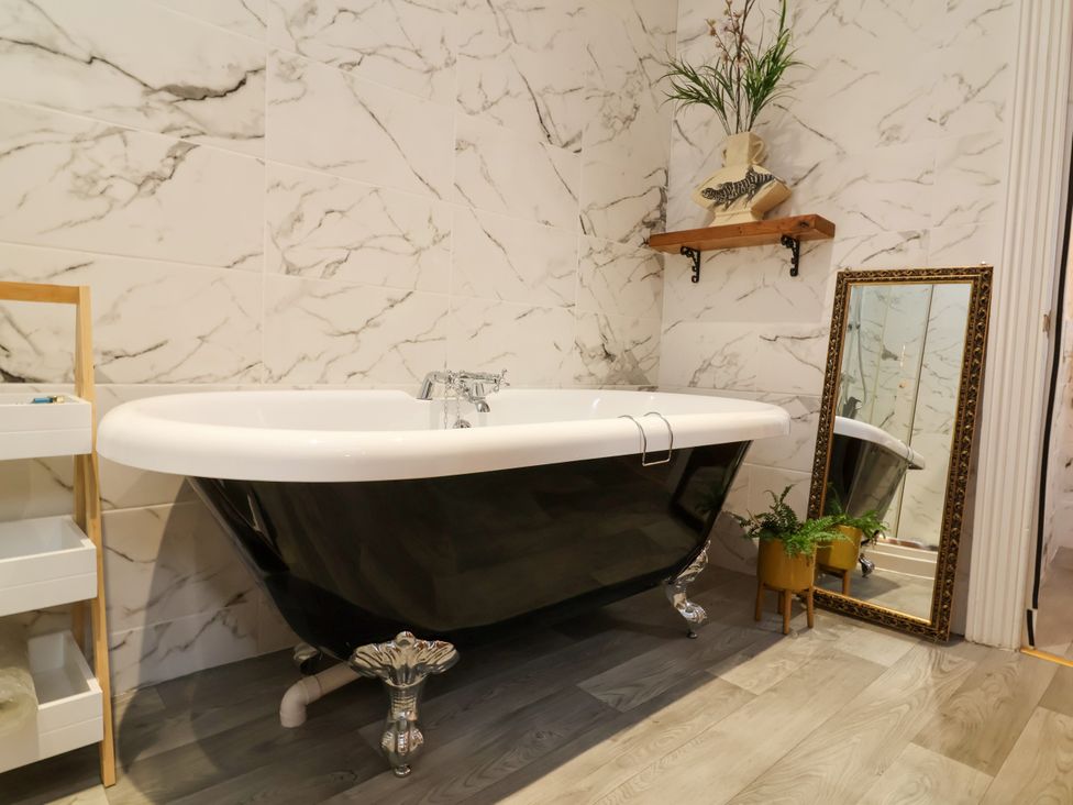 A bathroom with a bathtub and a mirror at Baywatch (St. David's View) Lynton