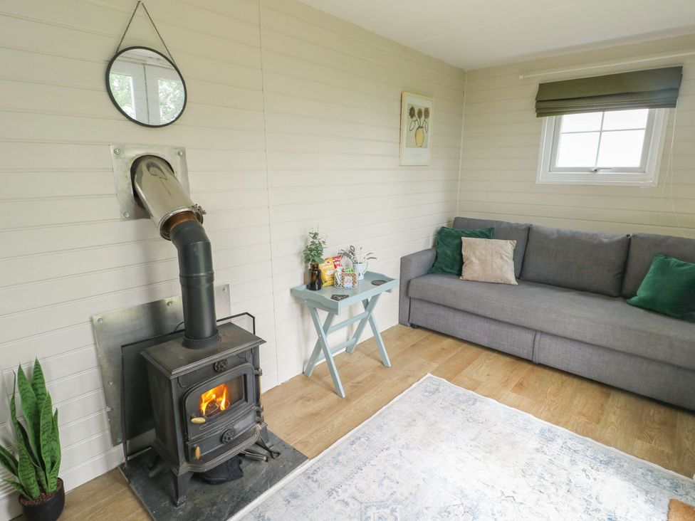 A living room with a stove and couch at Llewelyn Ty Croes