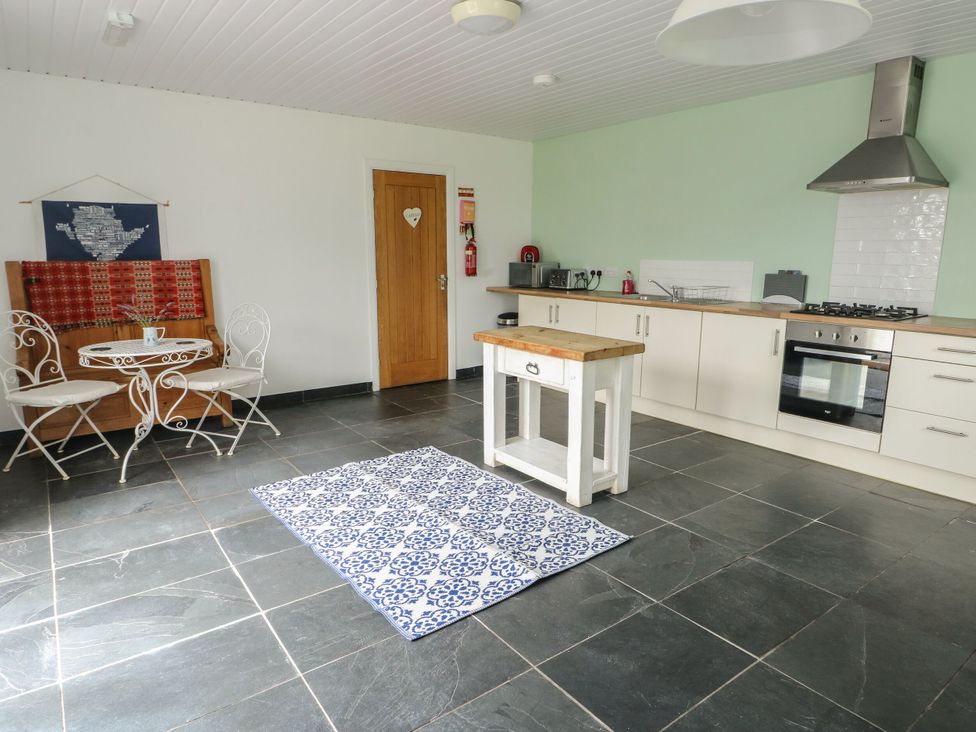 A kitchen with a dining area and appliances at Llewelyn in Ty Croes